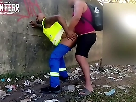 Two African American men having sex in public, one of them is dressed in work clothes.